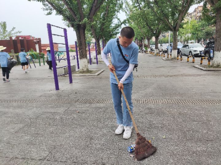 图为共创绿色乡村——志愿者清扫河边马路