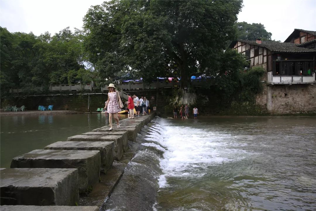 游客们在偏岩古镇的竹溪河畔游玩拍照在溪水环抱的偏岩古镇里游客们