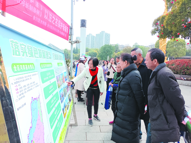 图为工作人员通过展板向过往市民宣传介绍《长江保护法》和《重庆市河