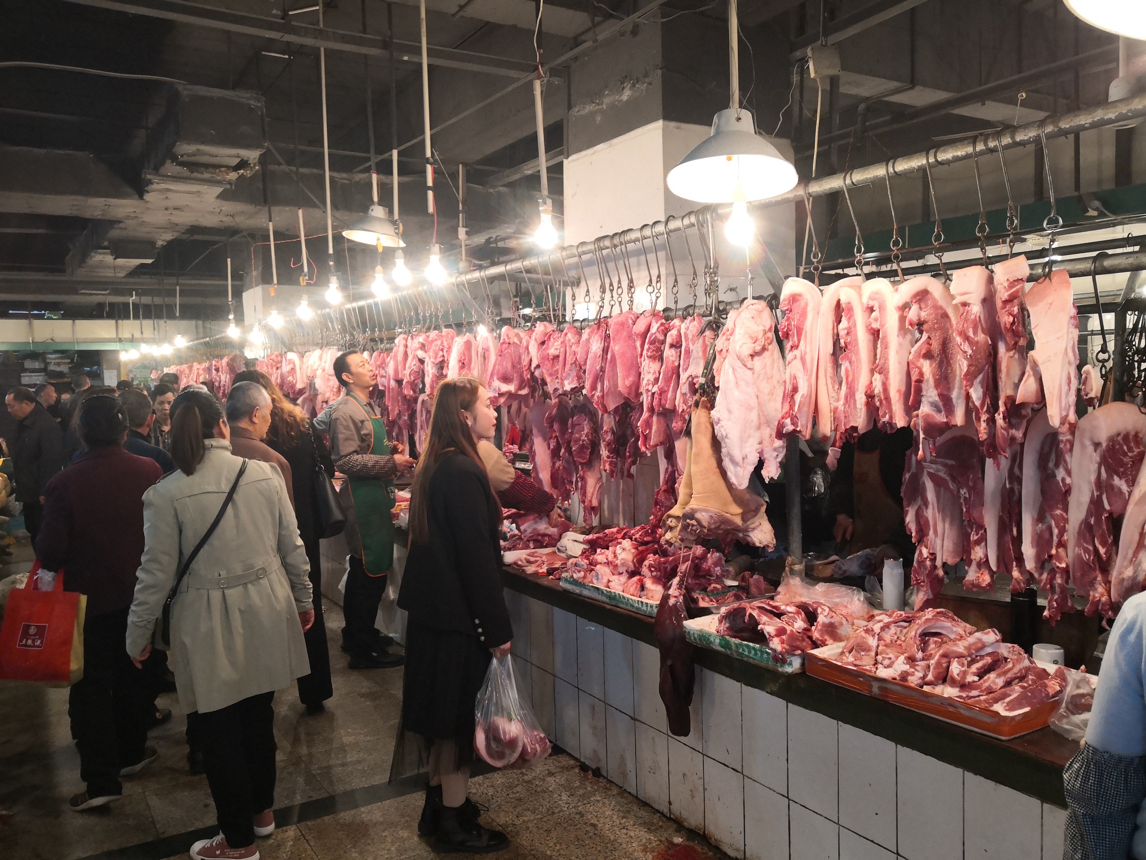 当天上午,在南门山新生菜市场,肉贩不断吆喝招揽生意,猪肉摊围了不少