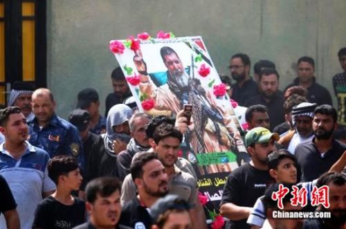 伊拉克民众在资深战士阿布塔辛葬礼上手举其照片。