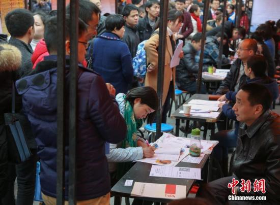 资料图：在武汉市纳杰人才市场招聘会上，挤满了前来应聘的求职者。中新社记者 张畅 摄
