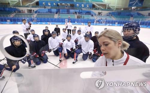 2月7日下午，在江陵市关东冰球中心，韩朝女子冰球联队主教练萨拉·穆雷（右一）给队员讲解战术。（图片来源：韩联社）