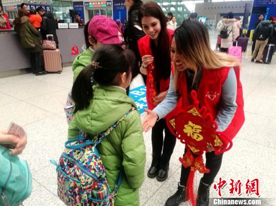 图为外国留学生志愿者向旅客赠送“福”字和中国结。　刘鹏 摄